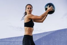 a woman holding a medicine ball in her right hand