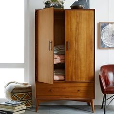 a tall wooden cabinet sitting next to a chair