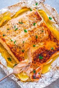 a piece of fish on foil with lemon sauce and parsley garnishes