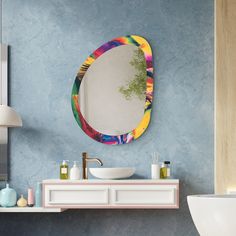 a bathroom with a sink, mirror and blue wall in the background that is decorated with multicolored paint