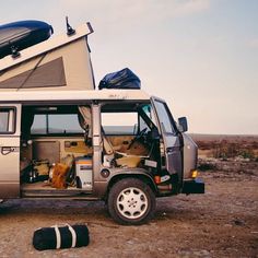 a camper van parked in the desert with its doors open and an awning on top