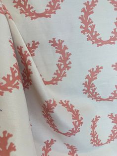 an orange and white fabric with red corals on it's side, as well as the letter o