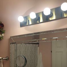 a bathroom mirror with three lights above it and a towel rack in front of the mirror