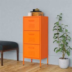 a tall yellow cabinet next to a potted plant on top of a hard wood floor