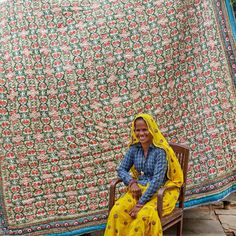 a woman sitting on a chair in front of a quilt