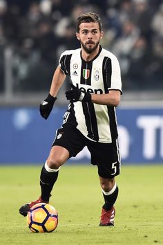 a man in black and white uniform playing soccer on field with crowd watching from stands