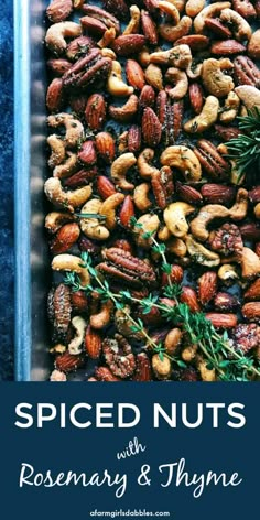 roasted nuts with rosemary and thyme in a baking pan on a blue background text reads spiced nuts with rosemary & thyme