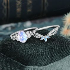 two rings with an opal stone and diamonds on them, sitting next to a book