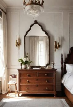 a bedroom with a dresser, mirror and chandelier in the middle of it