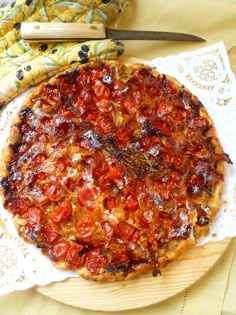 a pizza sitting on top of a white plate next to a knife and napkins