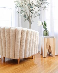 a living room with a round couch and potted plant on the side table next to it