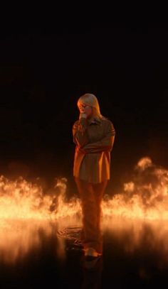 a woman standing in front of fire with her arms crossed