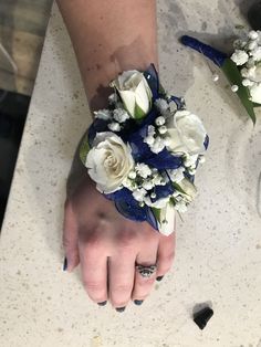 a woman's hand with blue and white flowers on it, next to another person's wrist