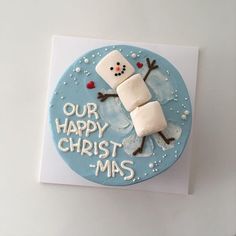 a frosted cake decorated to look like a snowman with the words our happy christ - mas on it