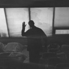 a man standing in front of a window with his hand up to the sky above him