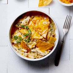 a bowl filled with food sitting on top of a table next to utensils