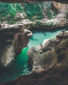 a person sitting on top of a rock next to a body of water in a cave