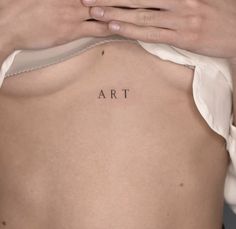 a woman's back with the word art tattooed on her left side ribcage