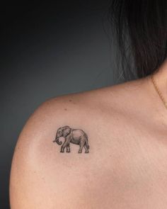 a small elephant tattoo on the back of a woman's upper arm and shoulder