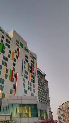 a tall white building with multicolored windows next to other buildings