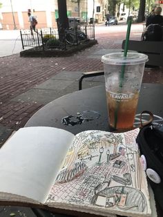 an open book sitting on top of a table next to a drink