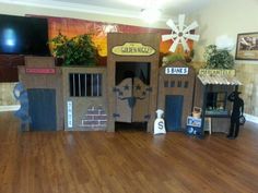 an indoor play area with wooden floors and fake buildings on the walls, windows, and doors