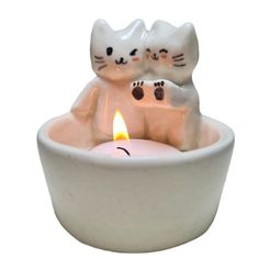 two cats sitting in a white bowl with a lit candle