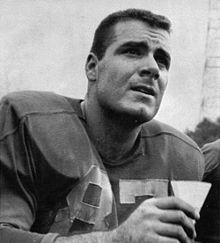 an old black and white photo of a football player holding a drink in his hand