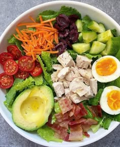 a salad with hard boiled eggs, bacon, lettuce, tomatoes and cucumbers