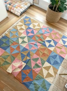 a large colorful rug on the floor next to a potted plant