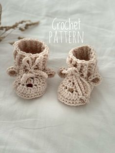 two crocheted baby booties sitting on top of a bed