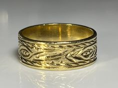 "Lovely antique wide gold band in solid 18K yellow gold. This beautiful antique ring measures 6.2mm north to south and is hand engraved on the outside with what appears to be a hand tooled floral theme. The band has a lovely patina and is in excellent condition. The age of this band is unknown. Ring size 5 1/4 and easily sized up or down several sizes. All hallmarks and patterns carefully preserved during sizing or restoration. Please allow three business days for sizing. One month layaway payme Heirloom Engraved Ring With Decorative Wide Band, Gold Decorative Thick Band Ring, Gold Wide Band Ring With Decorative Details, Gold Wide Band Ring With Decorative Design, Ceremonial Yellow Gold Engraved Ring With Decorative Band, Etched Gold Round Bands, Gold Engraved Ring With Wide Band Stamped 14k, Engraved Wide Band Ring Stamped 14k, Gold Engraved Wide Band Ring Hallmarked