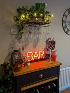 a bar sign sitting on top of a wooden table next to a wine glass rack