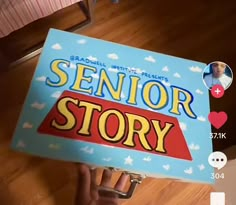 someone holding up a book with the title senior story written on it in front of their face