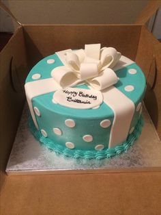 a blue and white birthday cake with polka dots on the bottom in a cardboard box