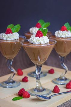 chocolate mousse with whipped cream and raspberries in small glasses on a table