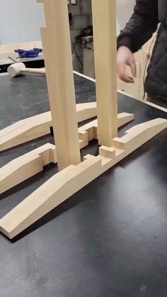 a person standing over a table with some wooden pieces on it and one hand reaching for something