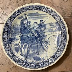 a blue and white plate with an image of two men on horseback