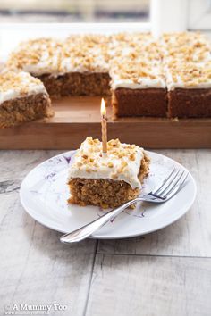 a piece of carrot cake on a white plate with a candle in the middle and a fork next to it