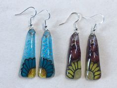 three earrings with different designs on them sitting next to each other