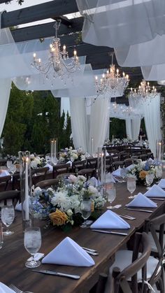 an outdoor dining area is set up with white linens and floral centerpieces