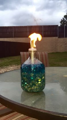 a table with a glass bottle on it and a lit candle in the top one