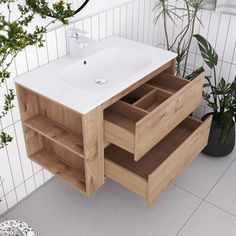 a white sink sitting under a wooden cabinet next to a potted plant and toilet