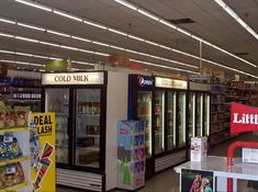 an empty grocery store filled with lots of items and signs on the walls, including soda machines