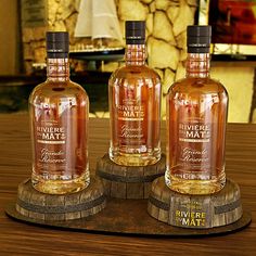 three bottles of beverage sitting on top of a wooden table