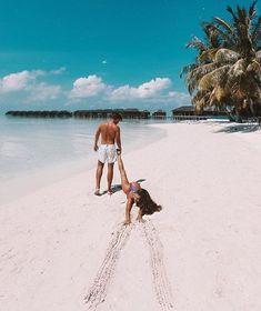 two people are playing in the sand on a beach