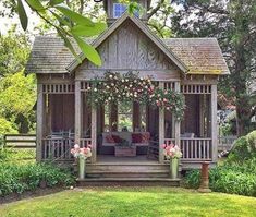 a wooden gazebo with flowers on the porch and steps leading up to an outdoor seating area