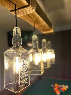 a pool table with several bottles hanging from the ceiling