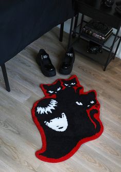 a pair of black and red shoes sitting on top of a wooden floor next to a bed