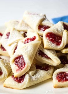 small pastries are piled up on a plate with powdered sugar and jelly toppings